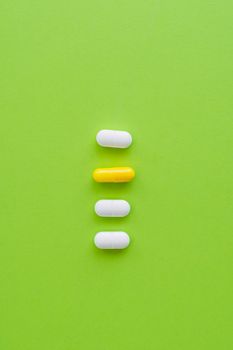 Five pills arranged on a bright green surface, highlighting pharmaceutical concepts.