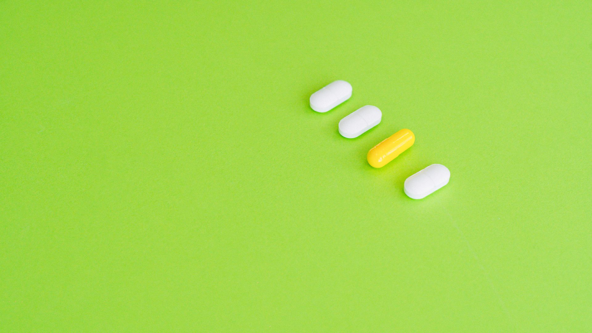 Armodafinil Benefits: Unlocking Cognitive Potential A row of white and yellow capsules on a green surface symbolizing medicine concept — armodafinil benefits