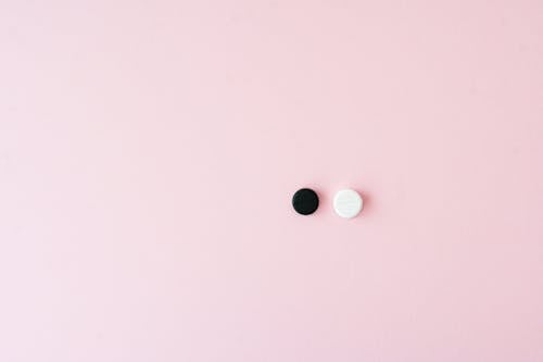 A Black and a White Pill on a Pink Surface