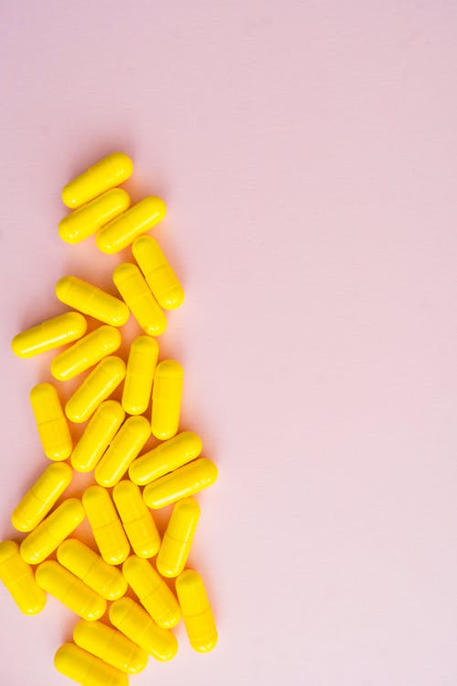 Free Yellow Medication Pill on White Surface Stock Photo