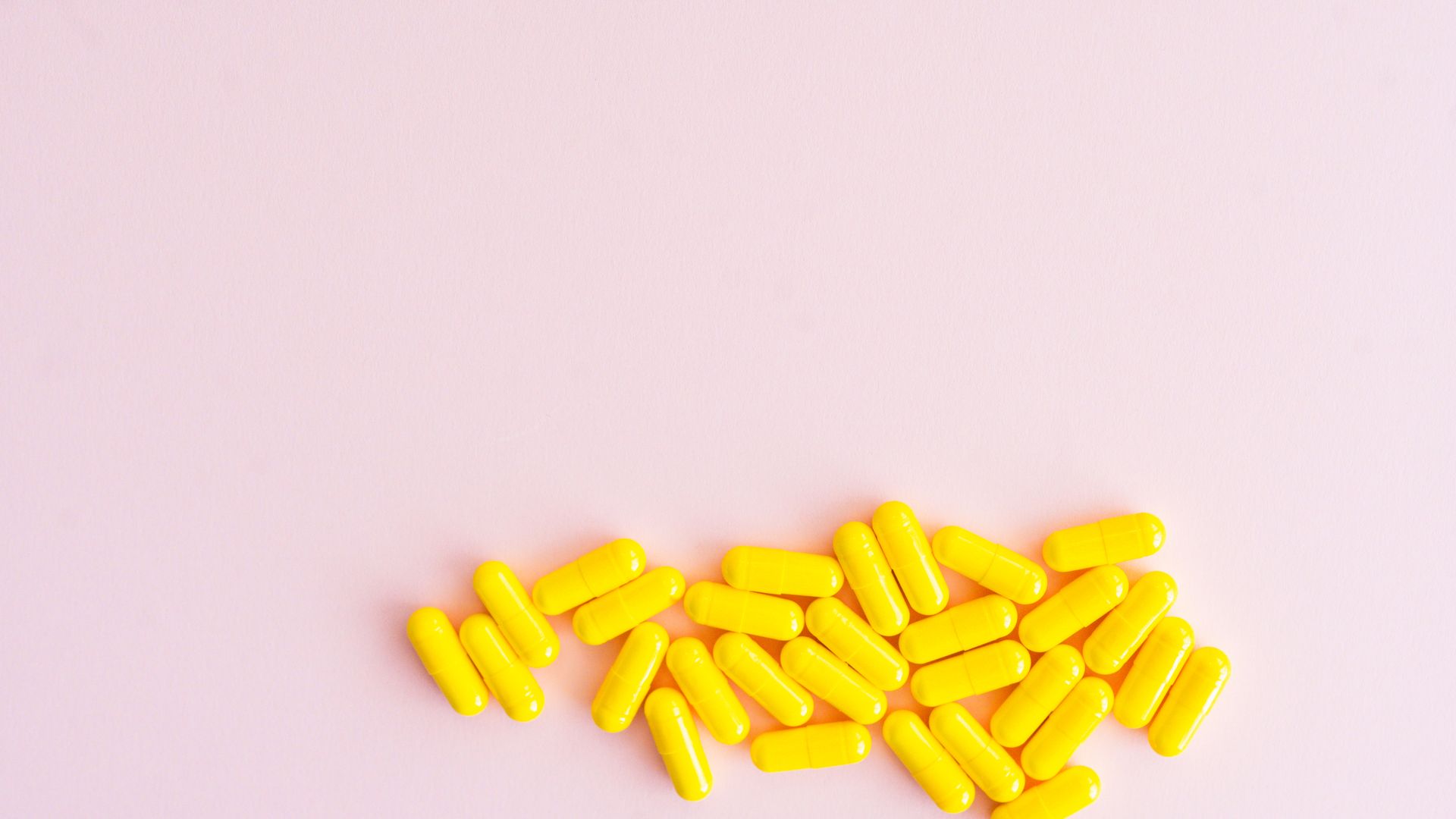 Modafinil vs Strattera: Unlocking Cognitive Potential Bright yellow capsules scattered on a pastel pink surface, offering medical and pharmaceutical themes — modafinil vs strattera
