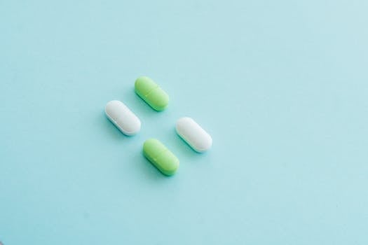 An assortment of green and white pills on a soothing blue surface.