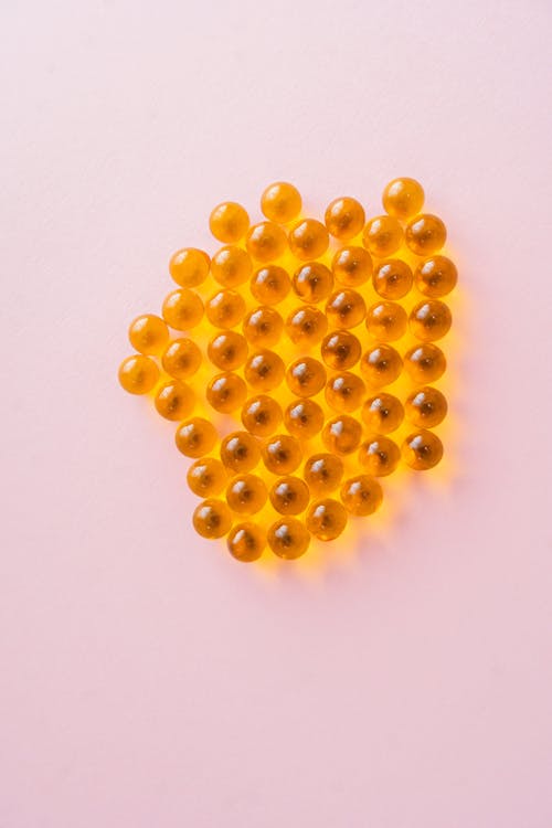 Round Orange Medicines on Pink Surface