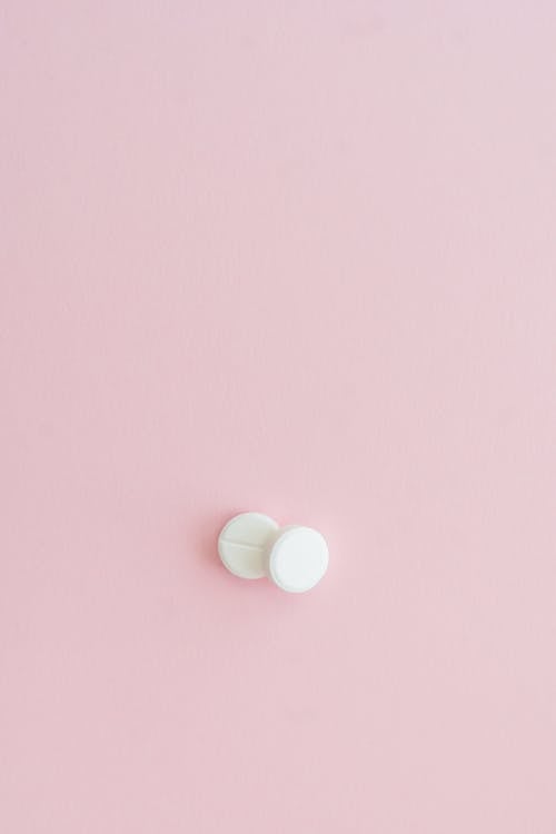 White Round Pills on Pink Surface