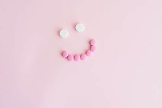 Pink and white pills arranged in a smiley face on a pastel pink background, representing healthcare positivity.