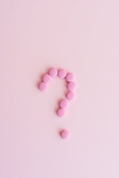 Close-Up Shot of Pills on Pink Surface