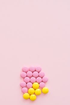 Arrangement of pink and yellow pills on pastel background, ideal for pharmaceutical themes.