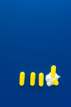 Yellow capsules arranged on a blue background with a cotton ball.