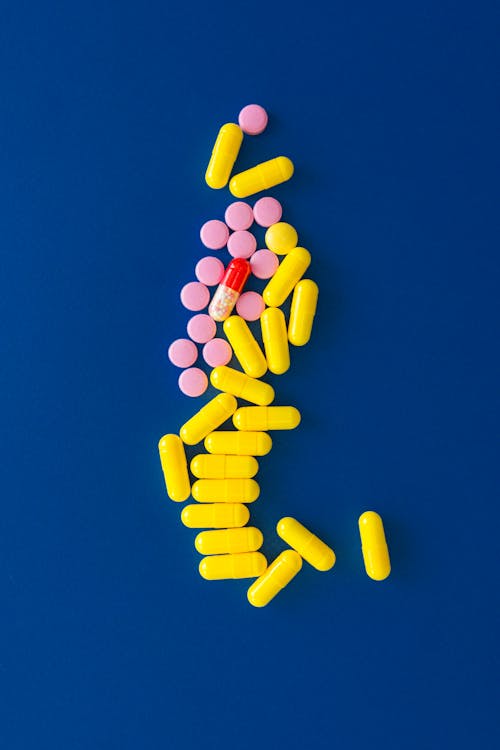 Pink and Yellow Pills on a Blue Surface