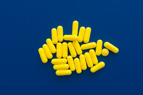 Free Yellow Medication Capsules on Blue Background Stock Photo