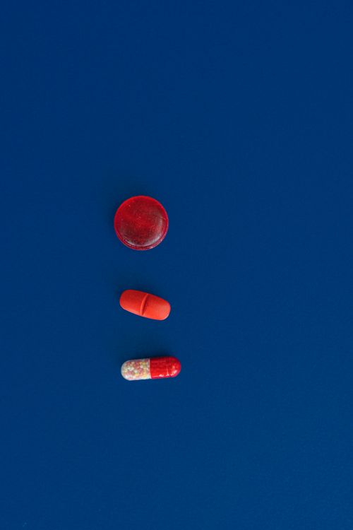 Free Various red pills and capsules lie on a blue surface, showcasing medical variety. Stock Photo