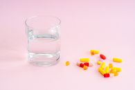 Clear Drinking Glass With Yellow and Pink Tablets