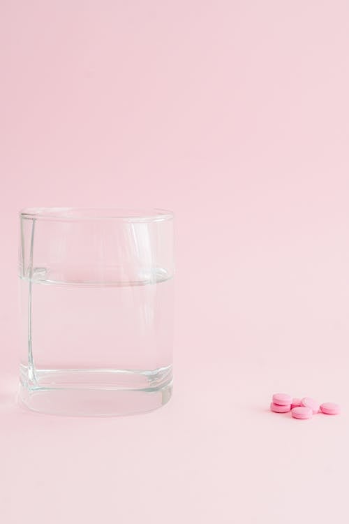 コップ1杯の水, ピンクの背景, ピンクの錠剤の無料の写真素材
