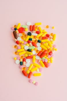 A vibrant collection of assorted medications and supplements on a pink surface.