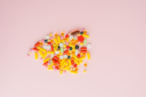 Free A vibrant collection of various pills and capsules on a soft pink background, emphasizing medication diversity. Stock Photo