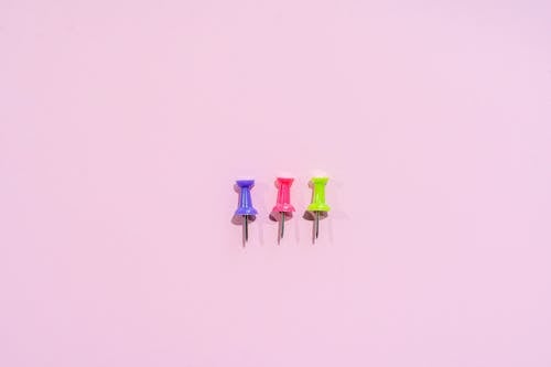 Free Colored Push Pins on Pink Background Stock Photo