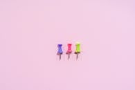 Colored Push Pins on Pink Background