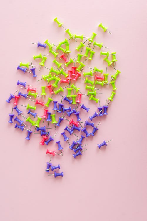 Assorted Push Pins on Pink Surface