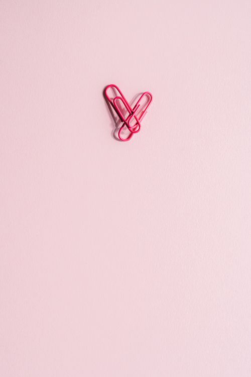 Free Artistic arrangement of red paper clips forming a heart on a pink background, showcasing minimalism. Stock Photo