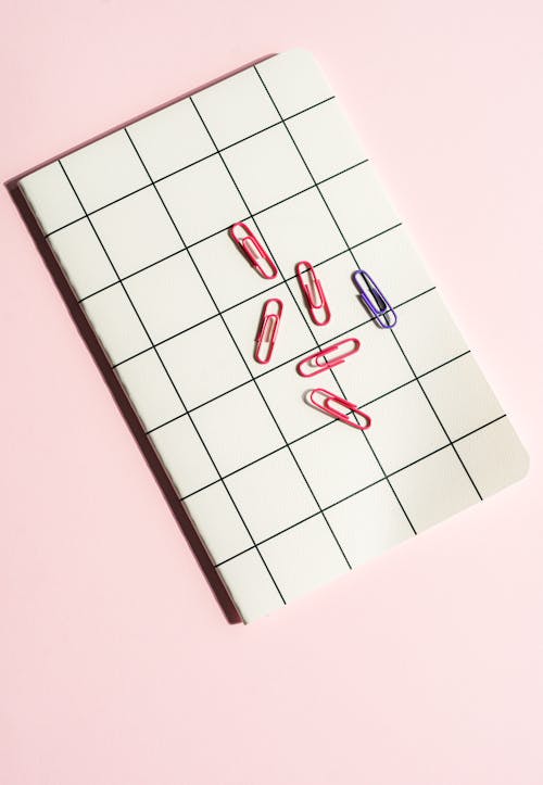 Foto profissional grátis de caderno, clipes de papel, fundo cor-de-rosa