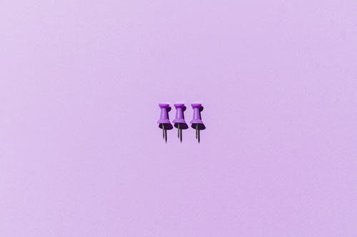 Close-Up Shot of Thumb Tacks on Purple Surface
