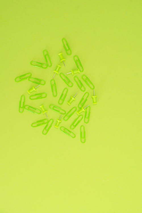 Paper Clips and Pins on a Green Surface