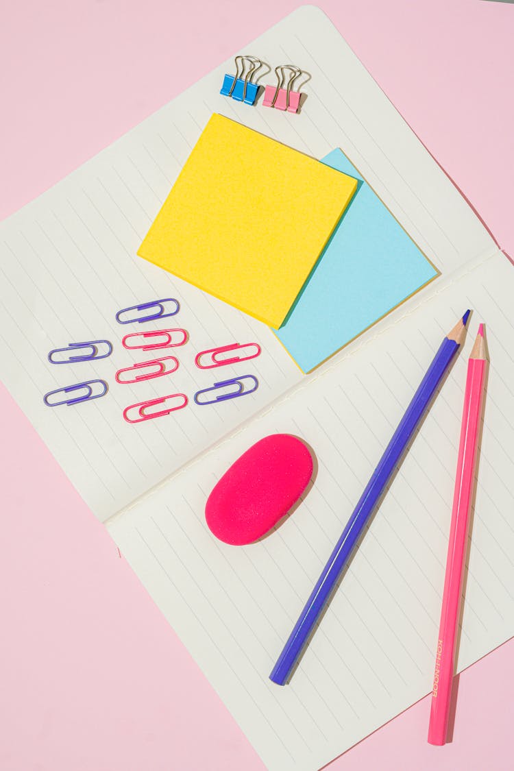 Colored Pencils And Clips On An Open Notebook