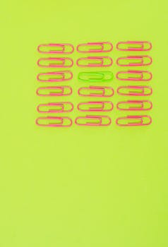 Pink and green paper clips arranged on a bright neon green background, highlighting color contrast.