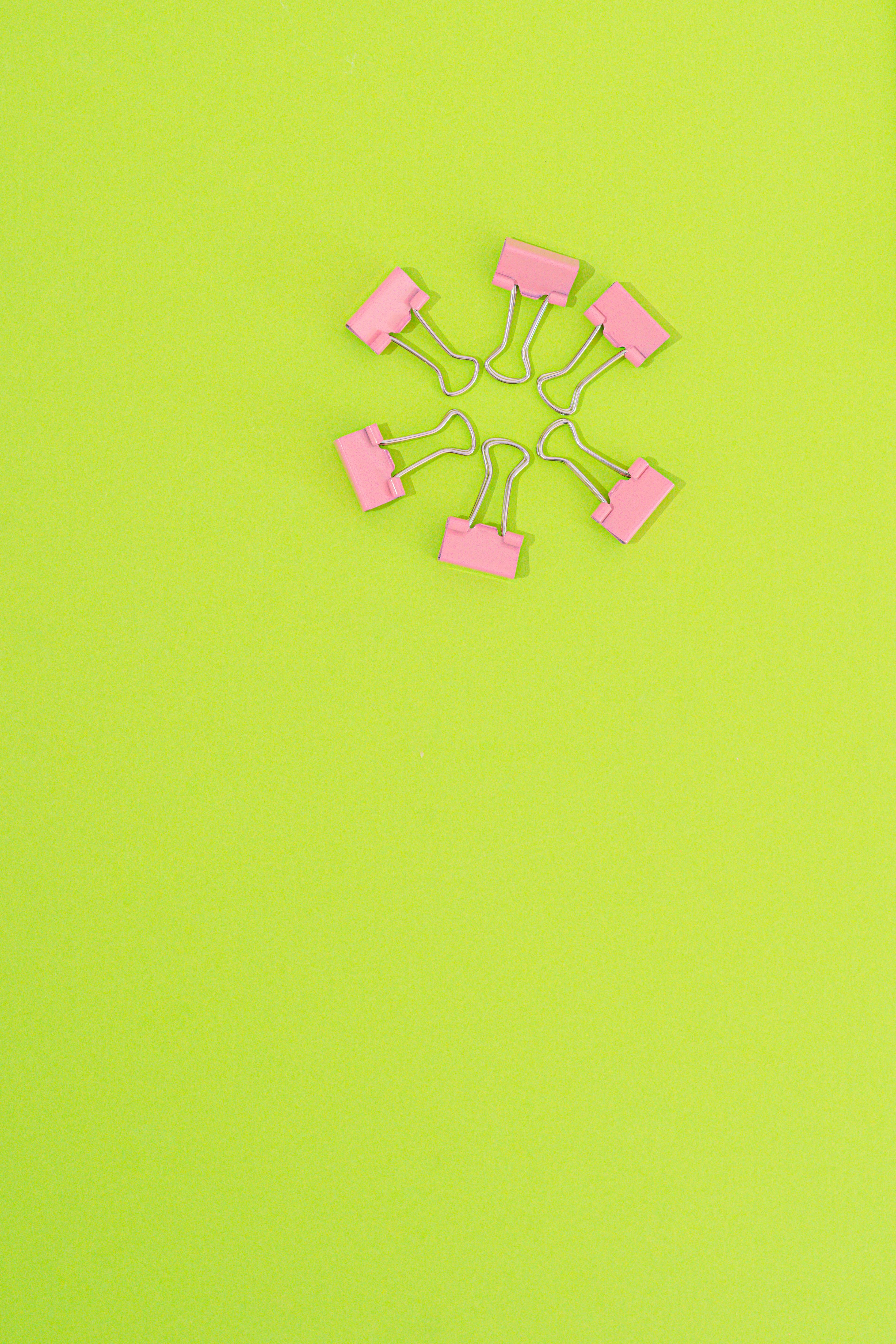 pink binder clips on a green surface