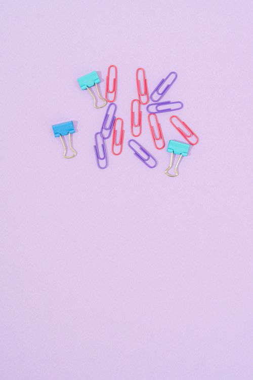 Free Vibrant binder and paper clips arranged on a pastel pink background with copy space. Stock Photo