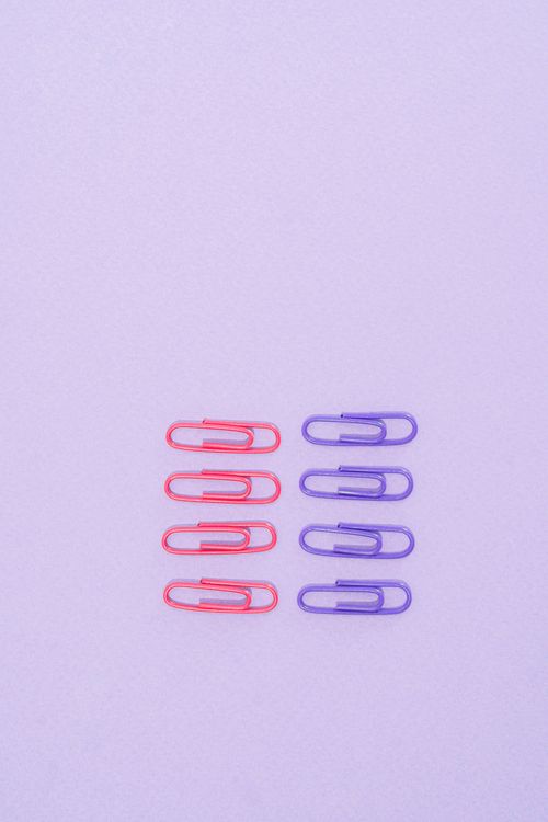 Free Red and purple paper clips arranged neatly on a pastel purple surface. Stock Photo