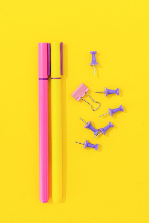 Free Bright and colorful pens with office supplies on a vibrant yellow surface. Stock Photo