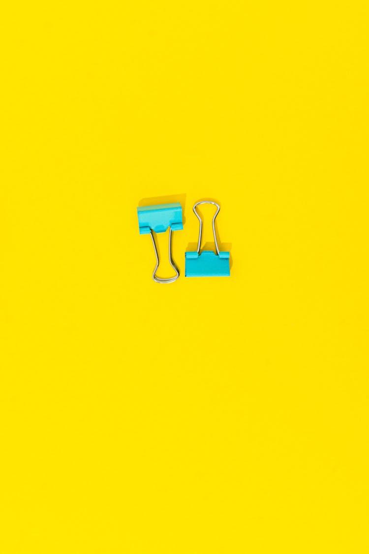 Teal Binder Clips In Yellow Background