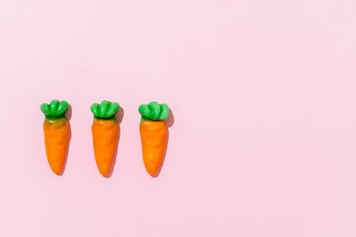 Three Plastic Carrots on Pink Background