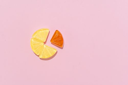 Free Colorful citrus-flavored candy slices arranged on a pink surface in a minimalist style. Stock Photo