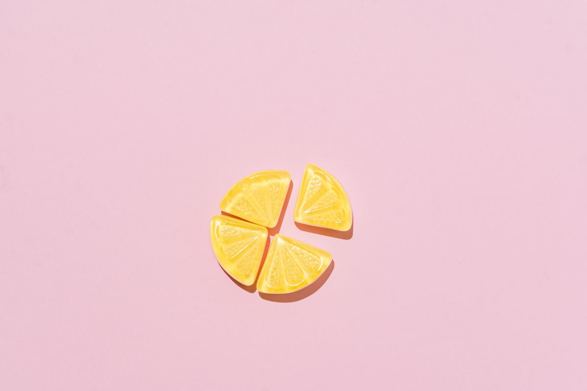 Top view of yellow candy slices arranged on a pastel pink background.