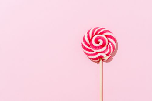Free A vibrant pink and white lollipop on a pastel pink background, perfect for sweet-themed designs. Stock Photo