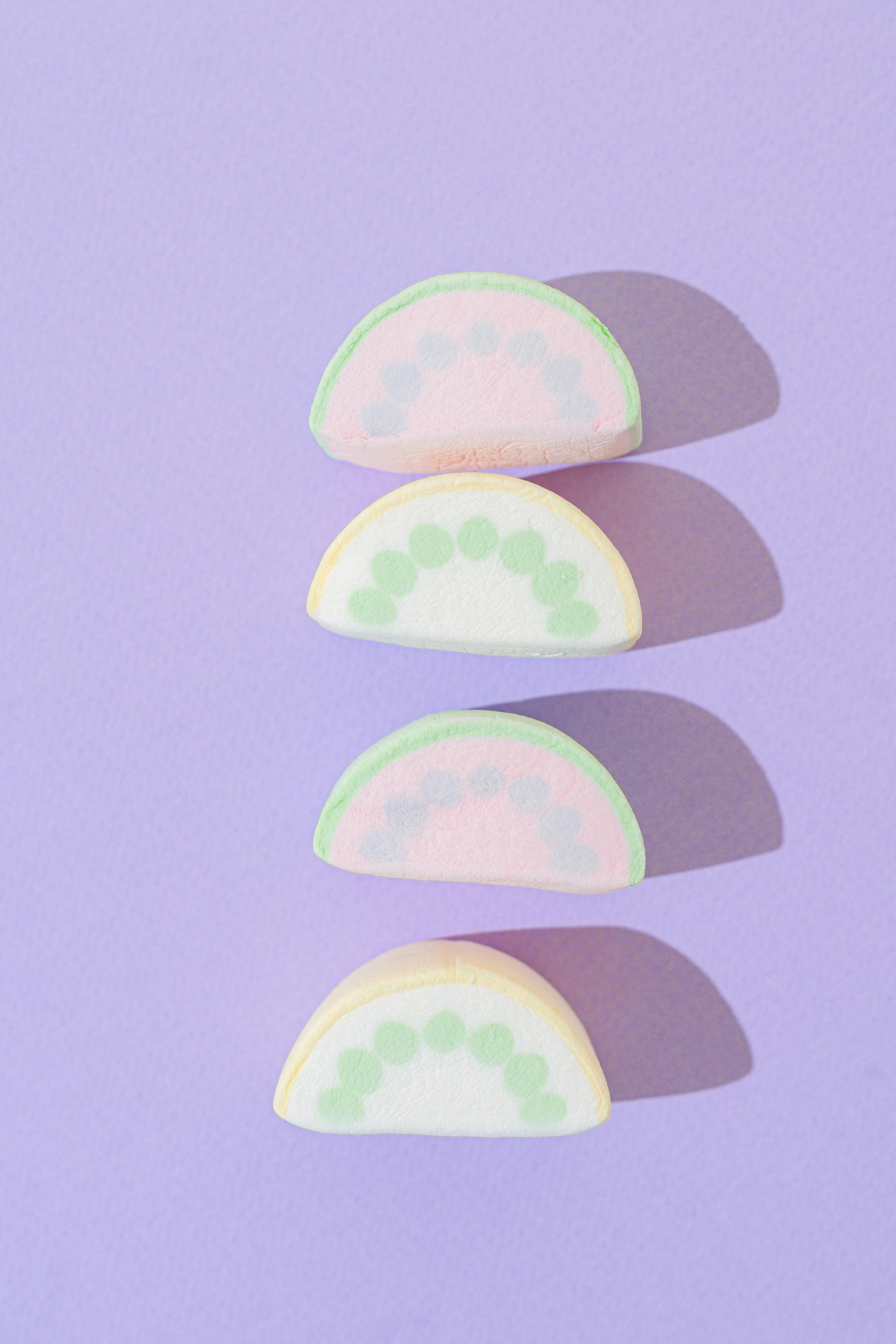 Four vibrant marshmallow slices arranged in a flatlay on a purple surface.