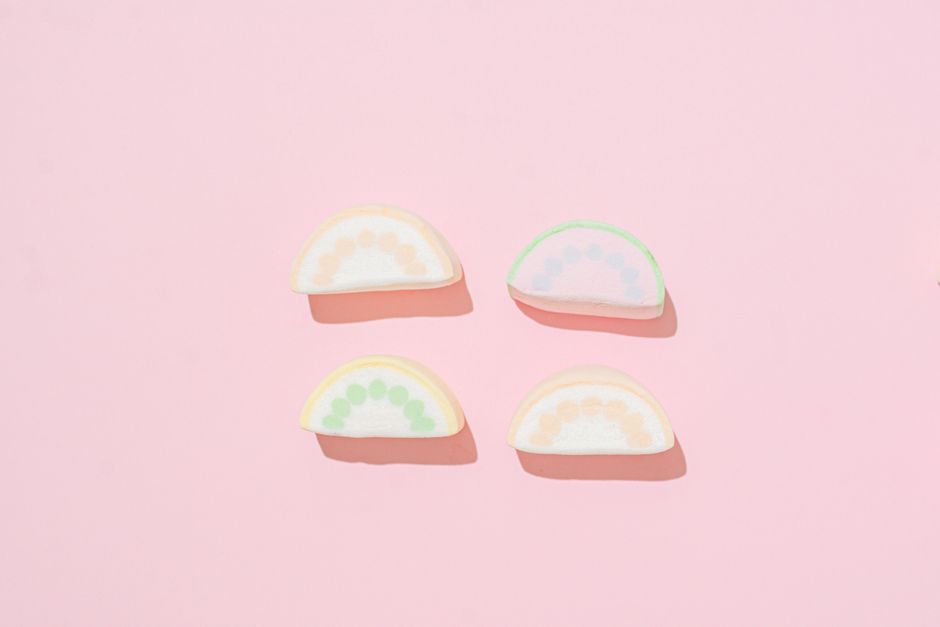Colorful marshmallow slices on a pastel pink background, creating a sweet and playful vibe.