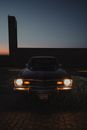 A Vintage Car Parked and Car Lights Turned on During Night