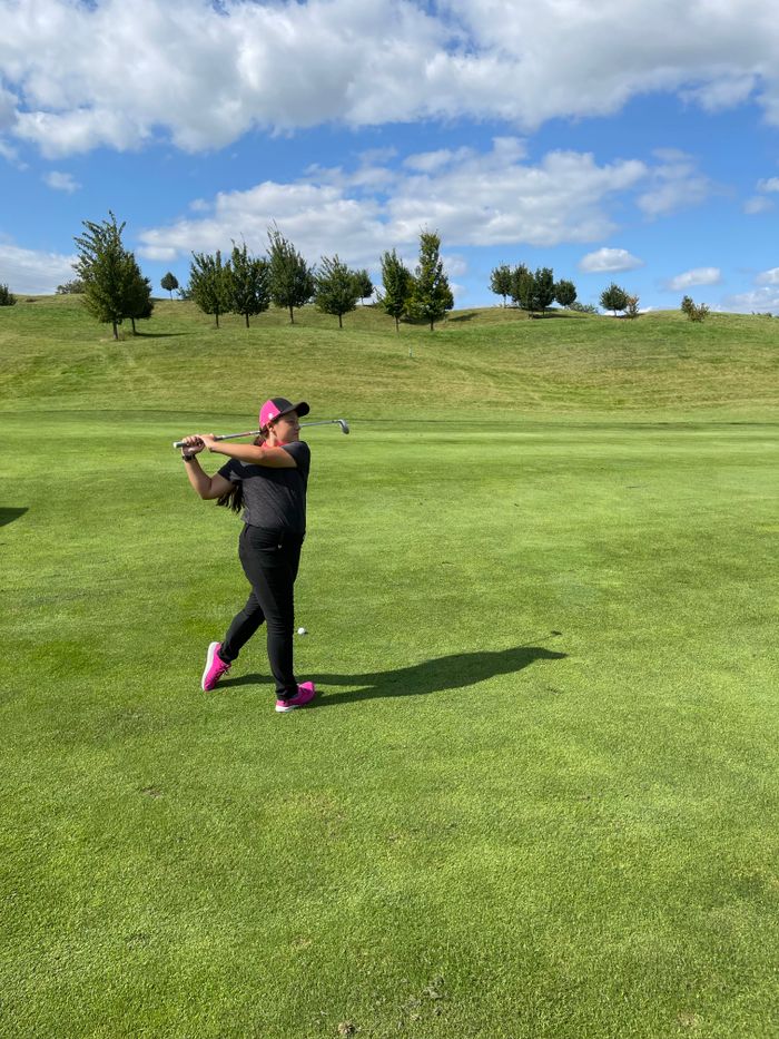 Woman golfer mid-swing during a personal lesson