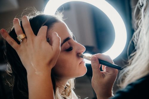 Free Close-up of a woman receiving makeup under a ring light by a professional artist. Stock Photo