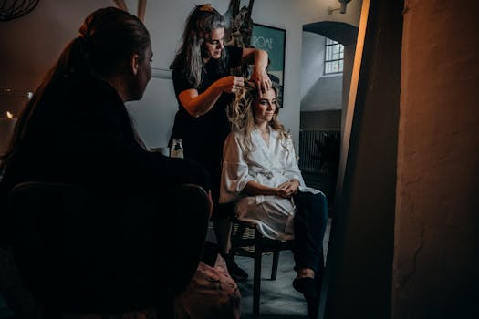 A hairstylist prepares a woman for an event in a warmly lit, intimate indoor setting. Ideal for lifestyle and beauty themes.