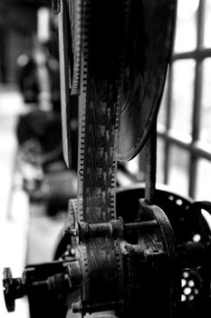 Close-up of an antique film projector showcasing film reels in monochrome.