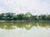 在印度德奥达尔的多云天空下，热带池塘倒映出绿树的宁静景色