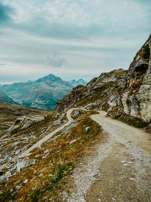 Free Explore the winding mountain path amidst rugged rocky landscape under a cloudy sky. Stock Photo