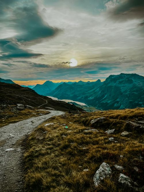 Free Explore a scenic mountain path under a dramatic sunset sky, perfect for adventure and travel inspiration. Stock Photo