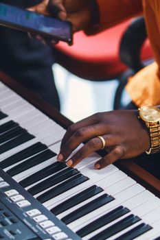 A person wearing a watch plays a digital piano keyboard, capturing musical creativity in action.