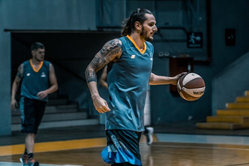 Man Holding Brown and White Basketball