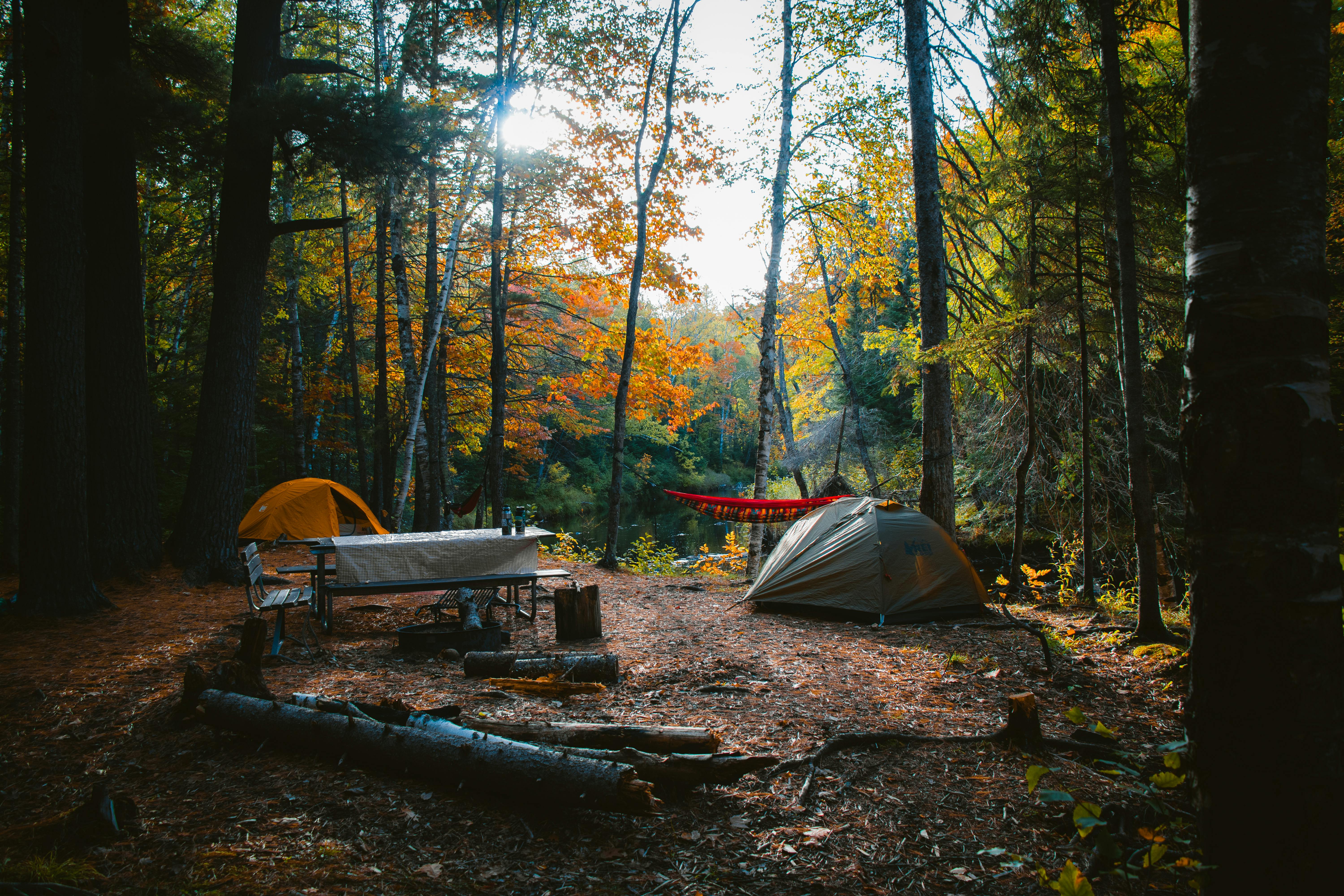 A serene camping site in a colorful autumn forest in Wisconsin, featuring tents and campfire setup.